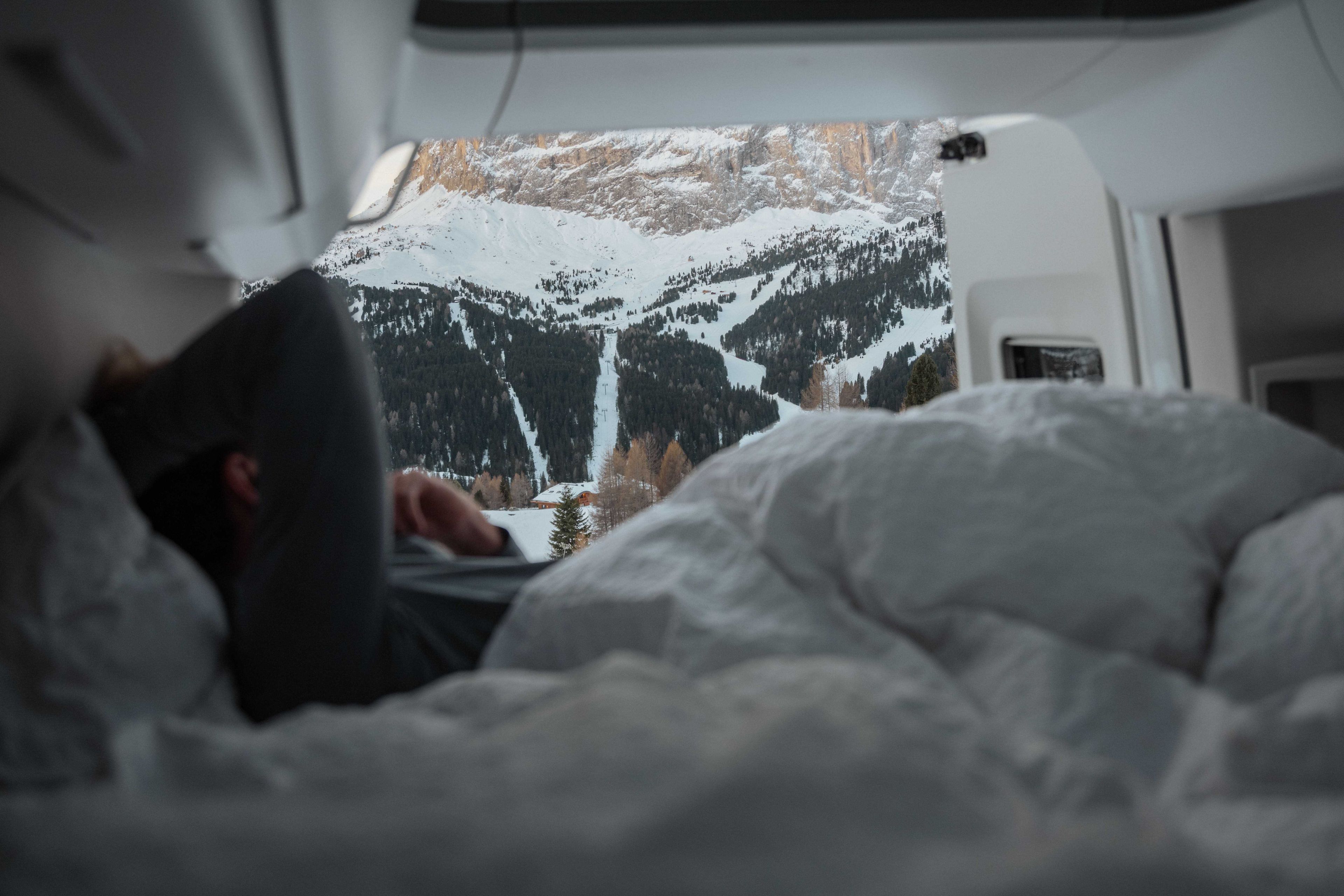 Sicht aus Camper-Bett auf verschneite Berglandschaft, Österreich
