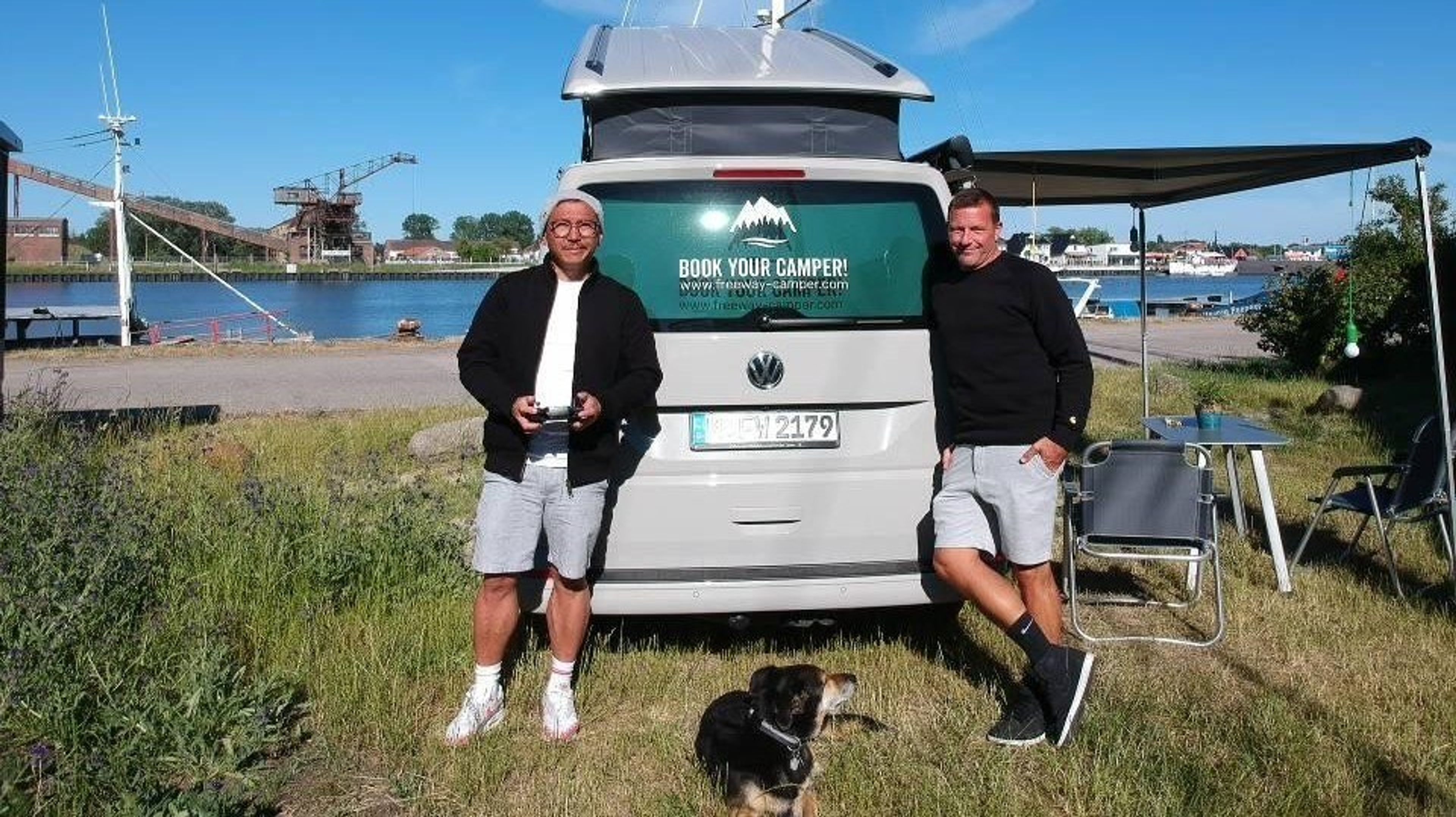 Mike e Marcus con il loro cane posano per la foto davanti al VW Bulli fronte lago