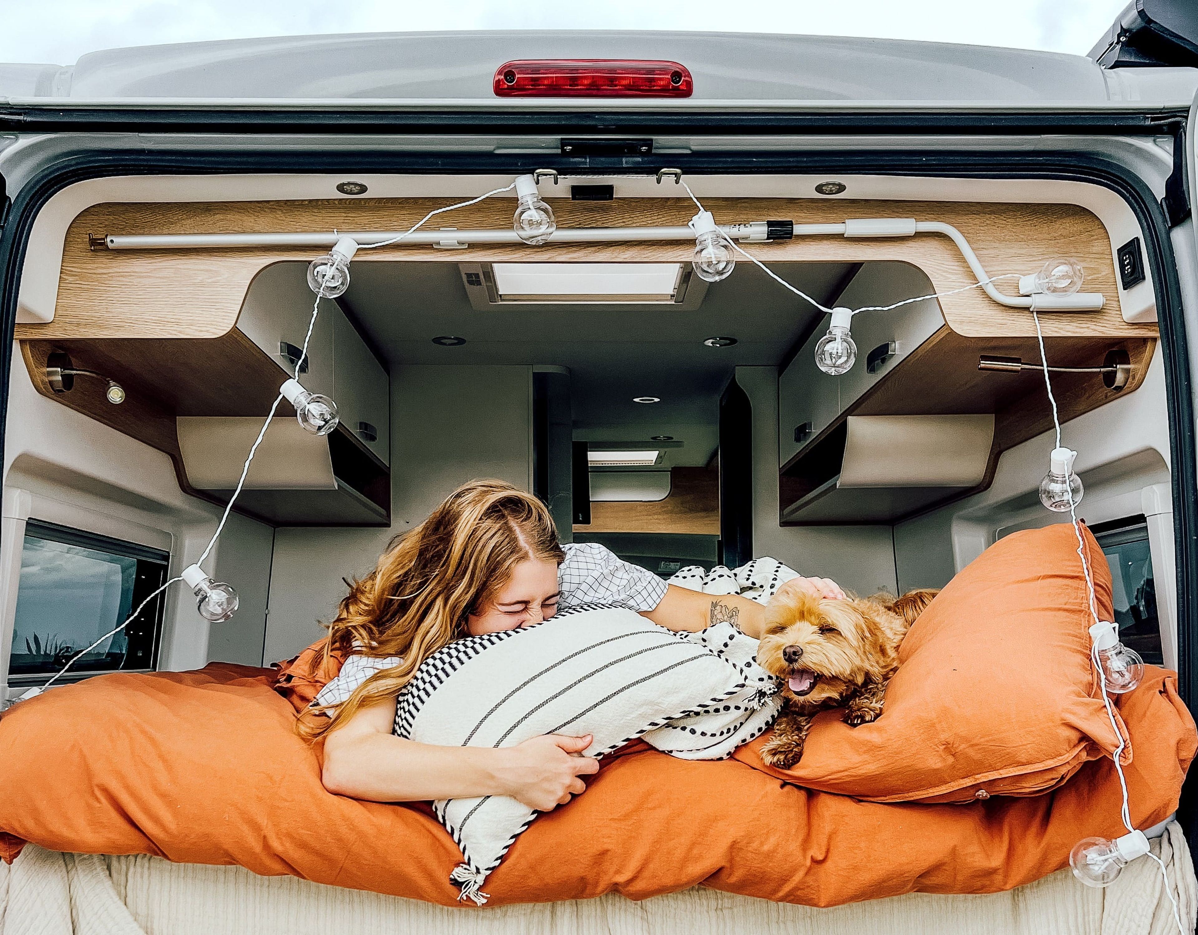 Glückliche Frau mit ihrem Hund im VW Grand California