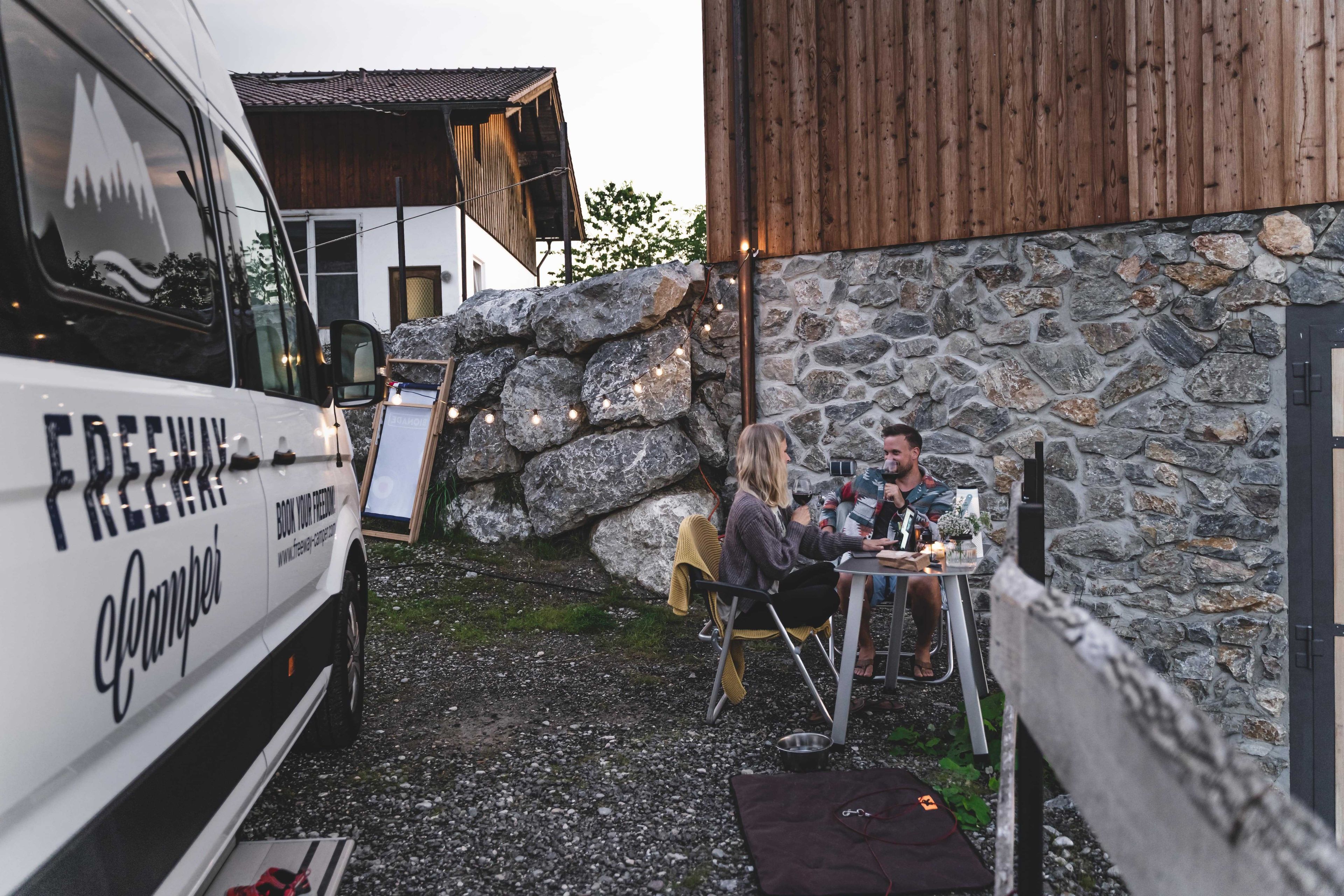 Couple sitting happily in front of white camper