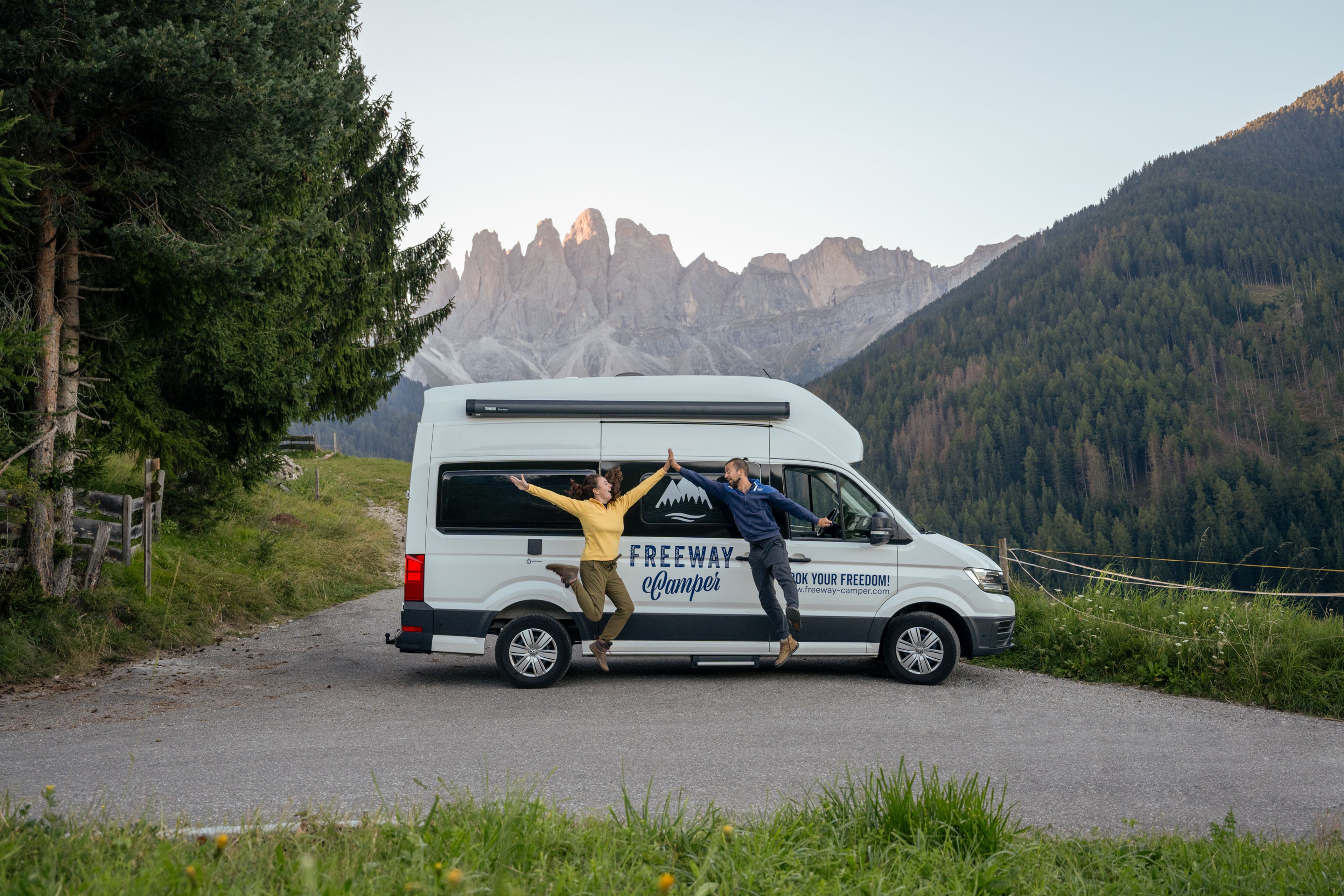 una coppia divertita pronta per una foto davanti al camper tra le montagne delle Dolomiti