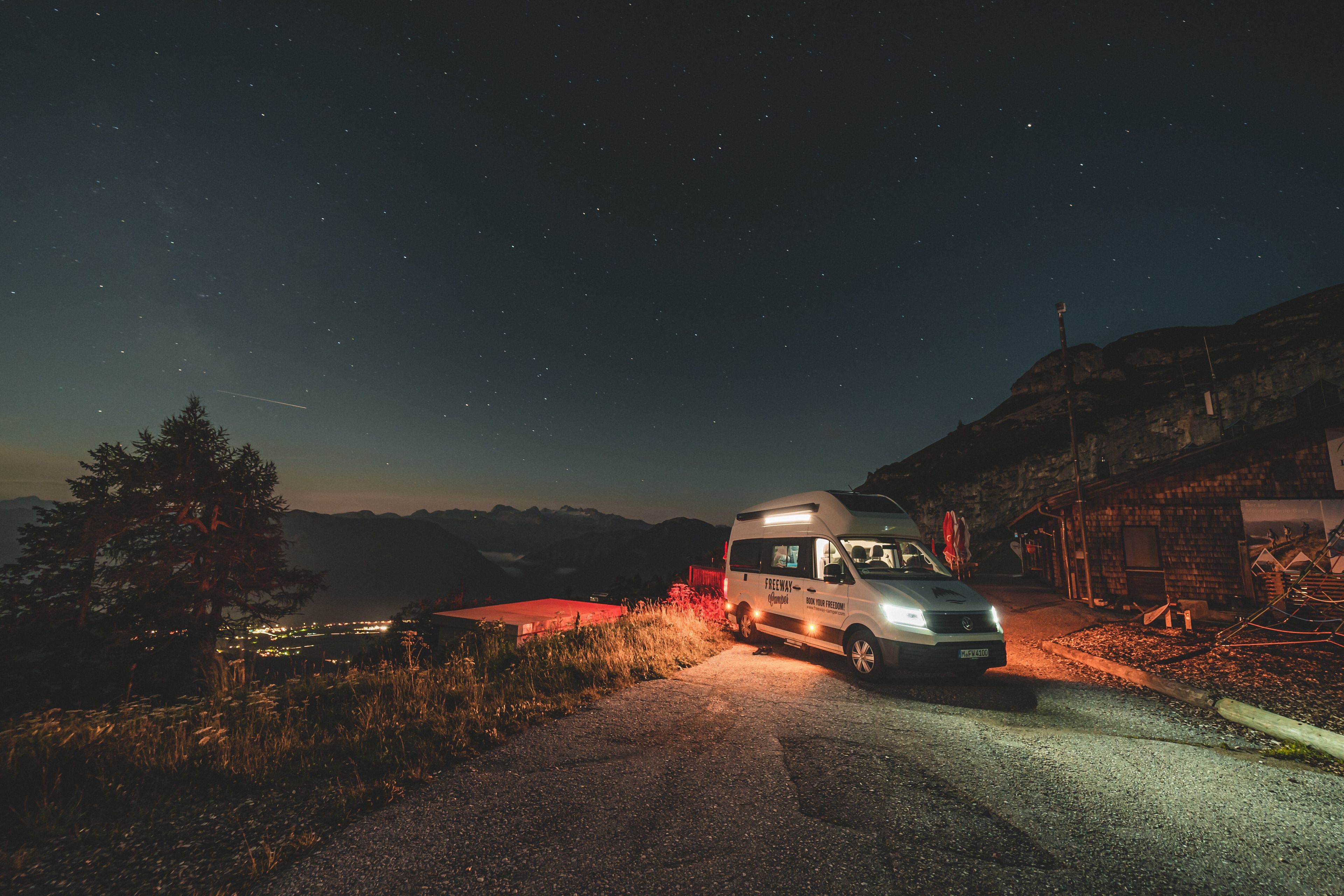 FWC Campervan steht auf nächtlicher Straße in den Bergen vor einem Sternenhimmel.