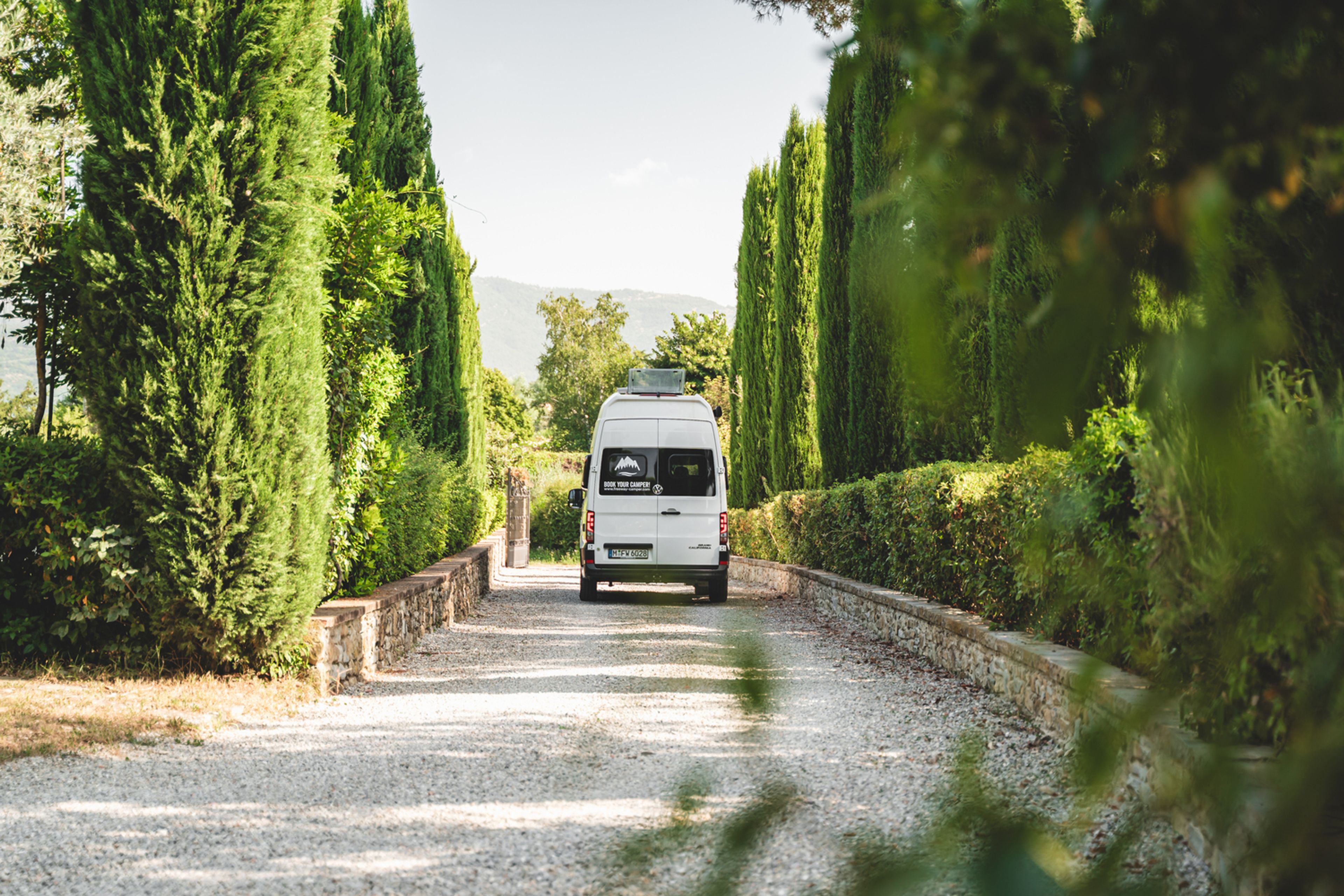 Camper VW Grand California 600 tra il verde degli alberi in Toscana