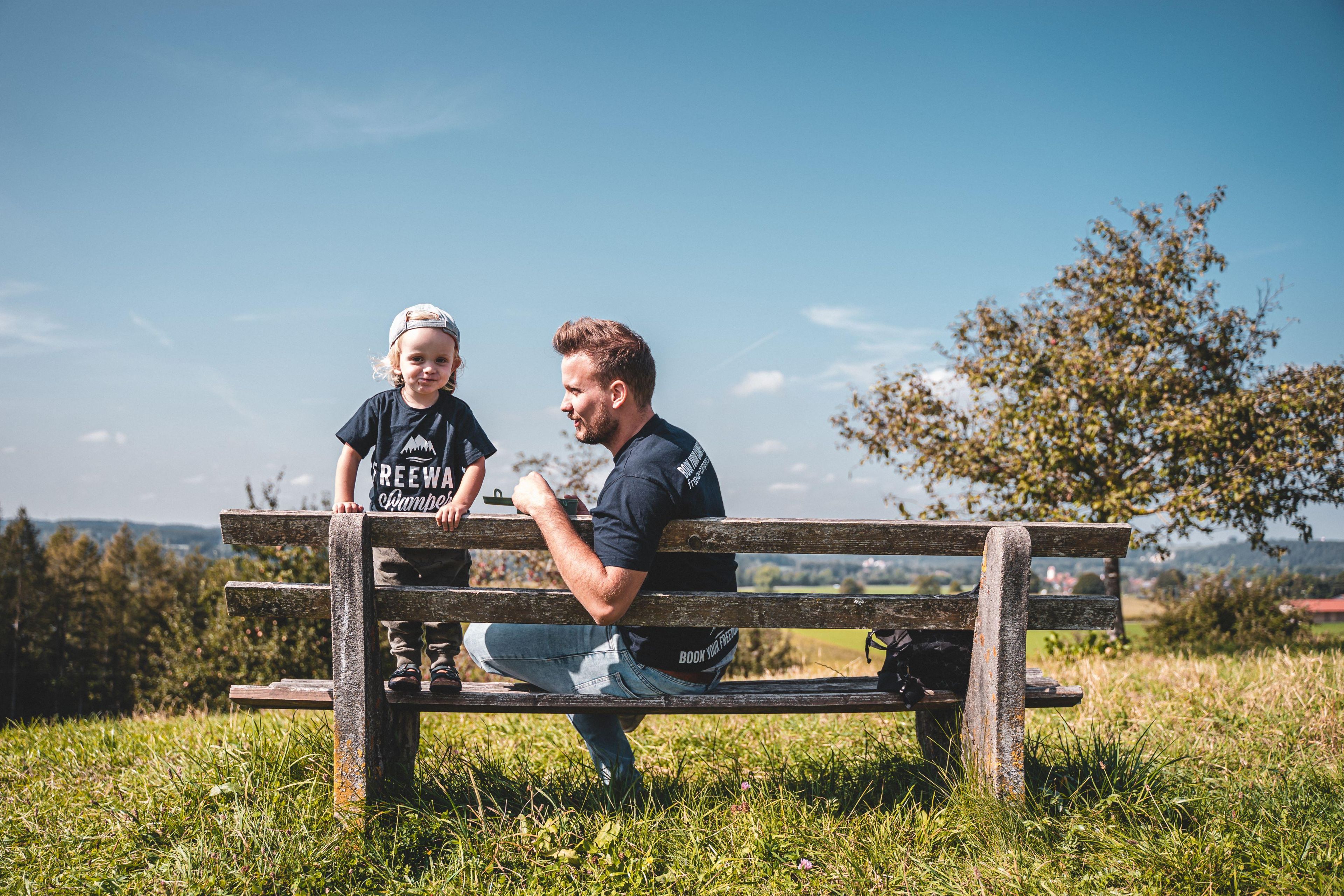 Padre e figlio su una panchina del parco con la maglietta FreewayCamper