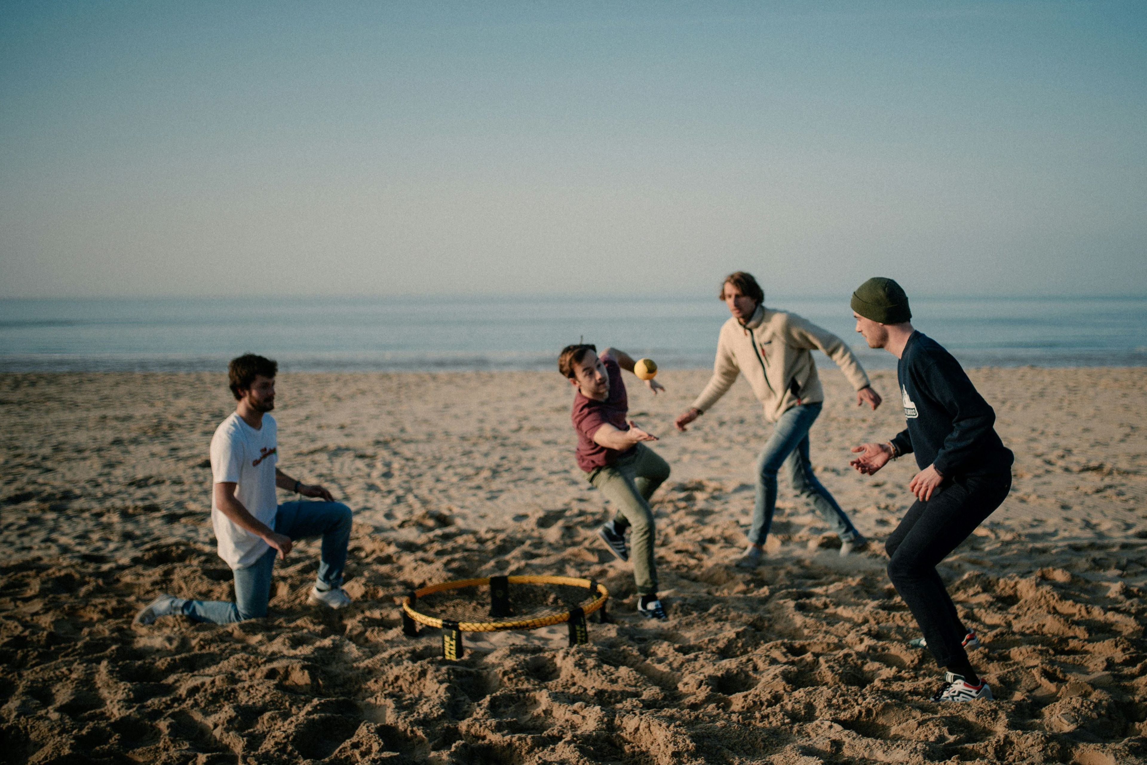 Vier Freunde spielen Spikeball am Strand