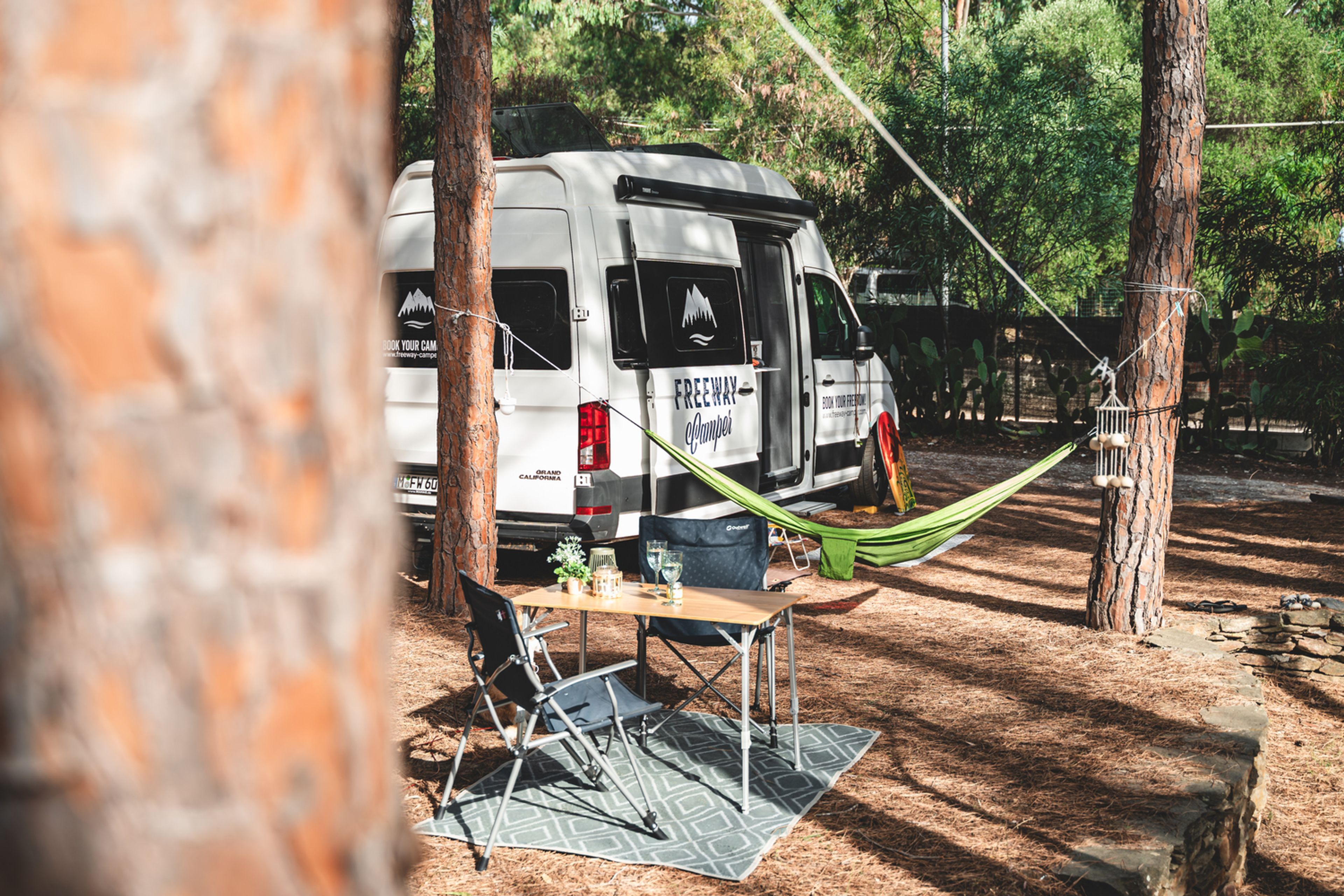 Camper VW vicino a un'amaca in un campeggio in Liguria tra gli alberi