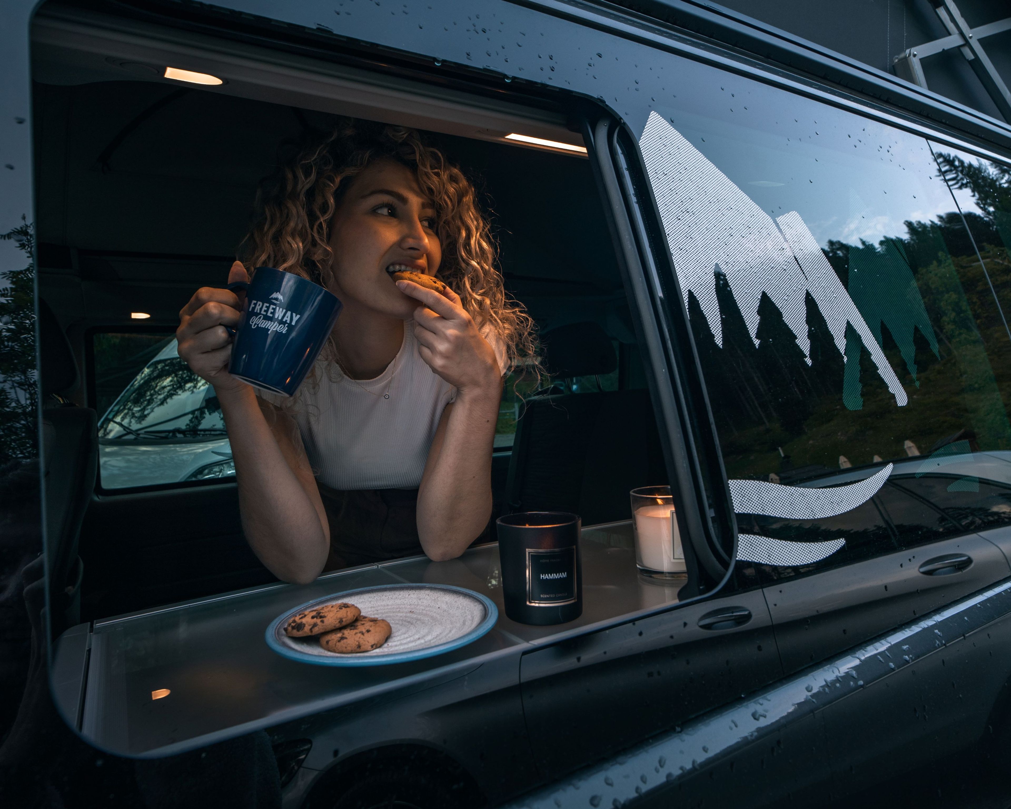 Diese junge Frau hat es sich mit Keksen im VW Bulli bei Regen bequem gemacht