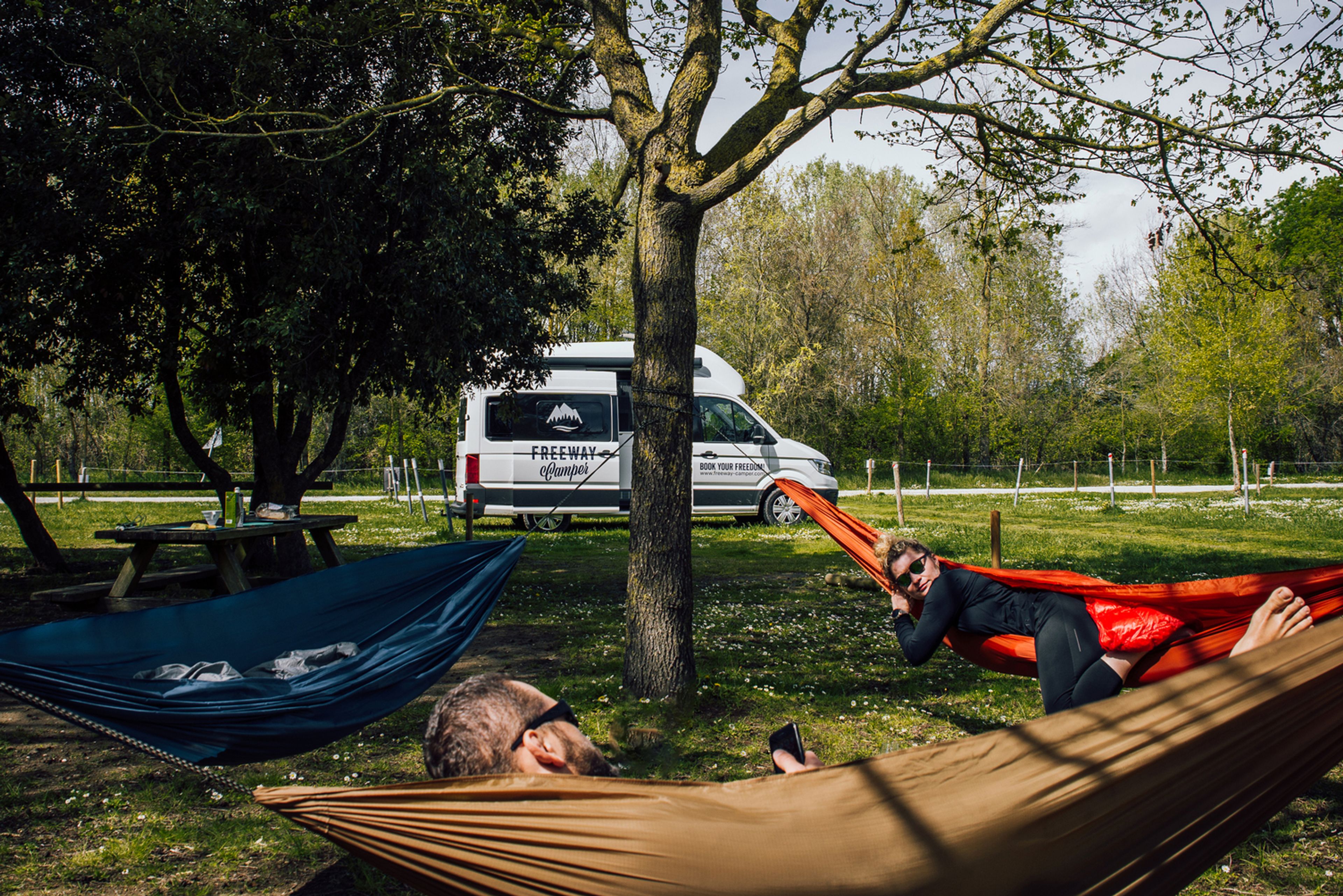 Amici in viaggio in camper che si rilassano sulle amache in un campeggio in Slovenia