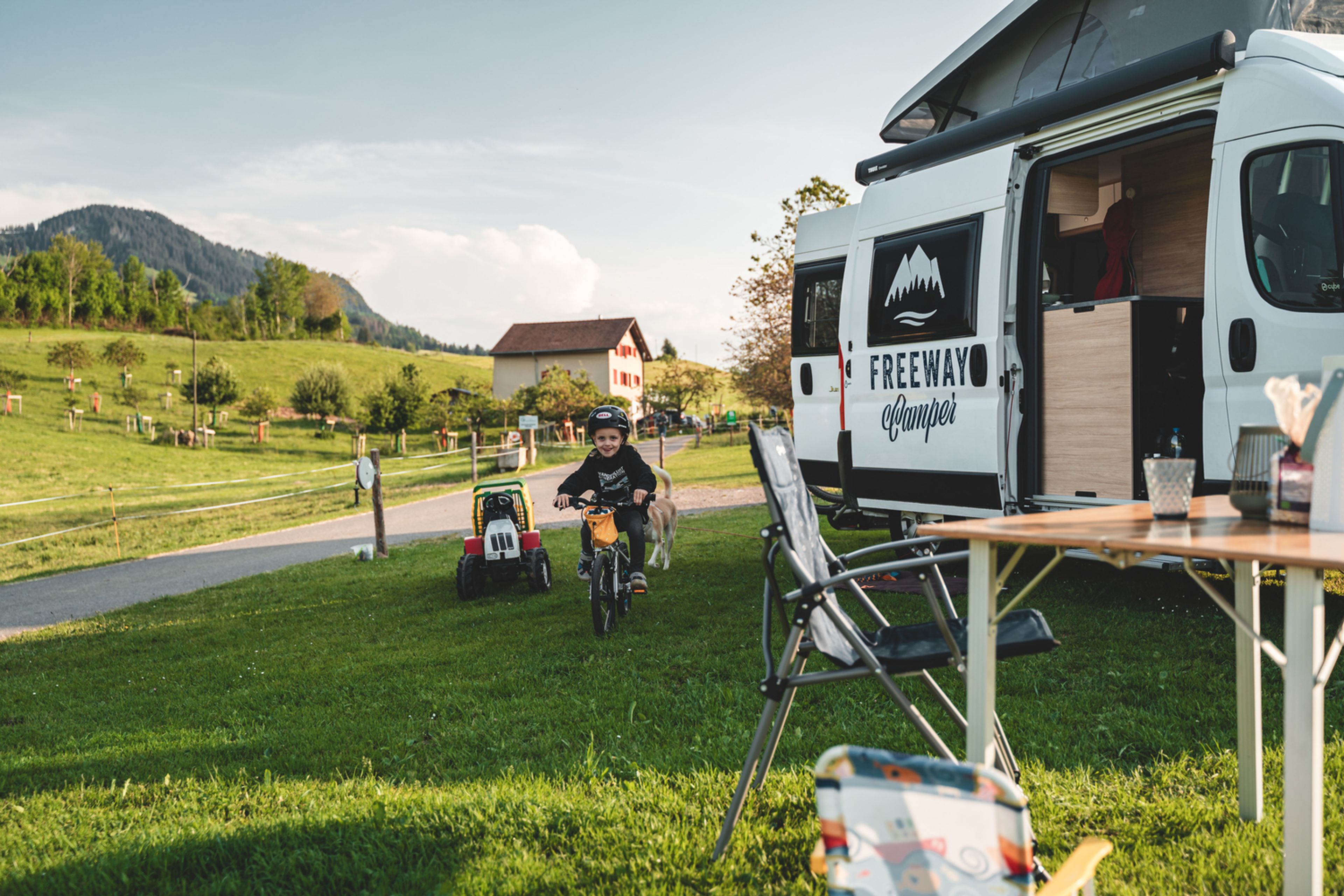 Un bambino gioca con la sua bicicletta e i suoi giocattoli durante un viaggio in camper in Svizzera