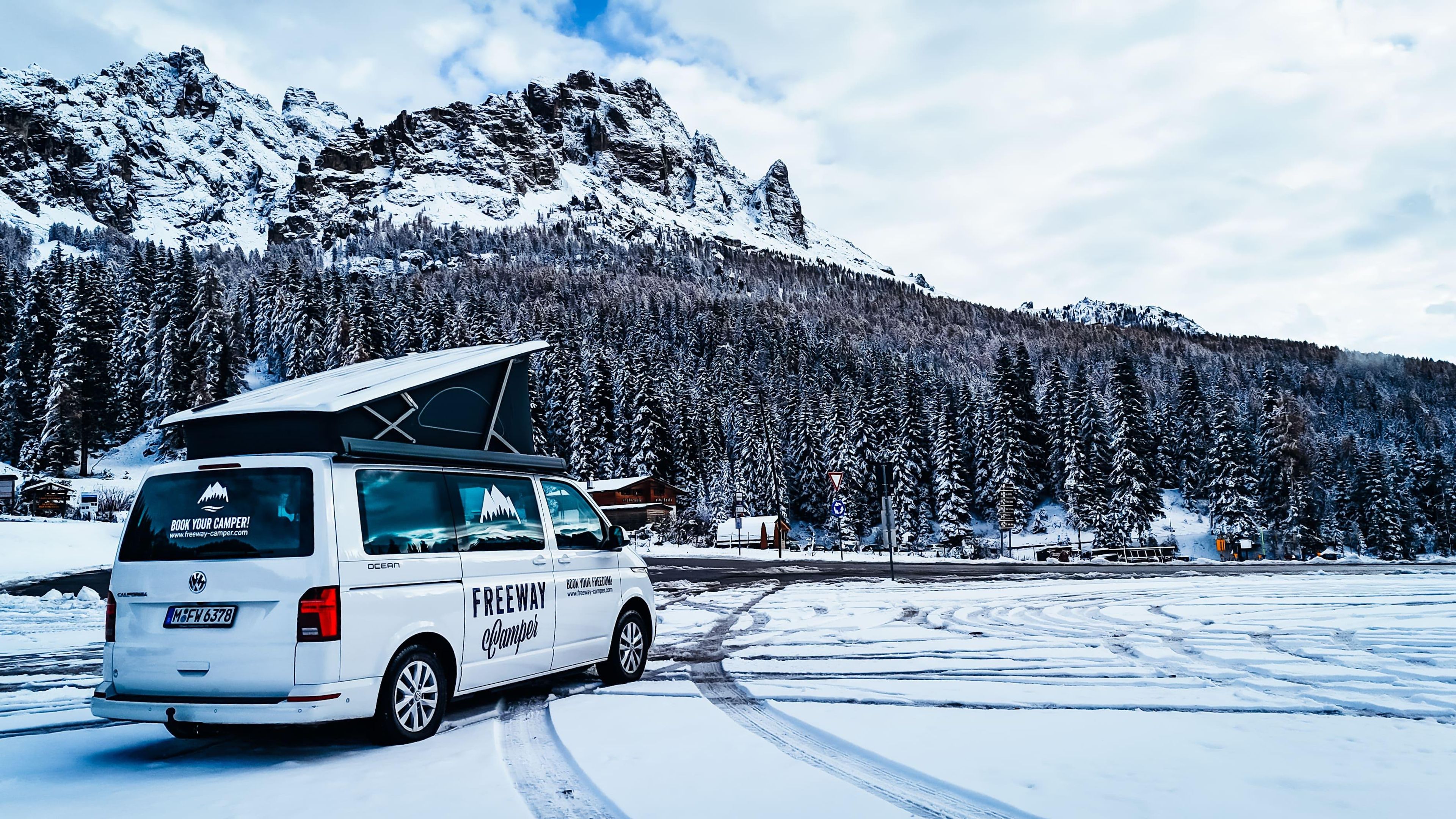 VW Bulli mit Aufstelldach im verschneiten Gebirge, Italien