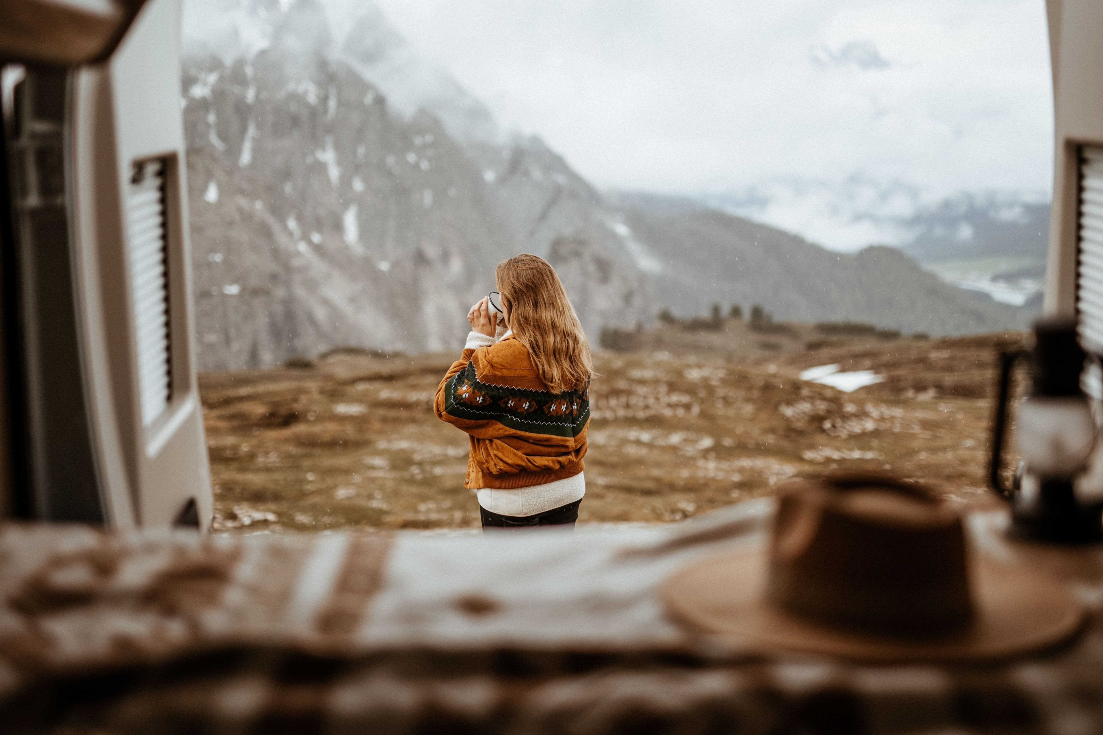 Eine allein reisende Frau beim Kaffeetrinken, Blick aus dem Camper