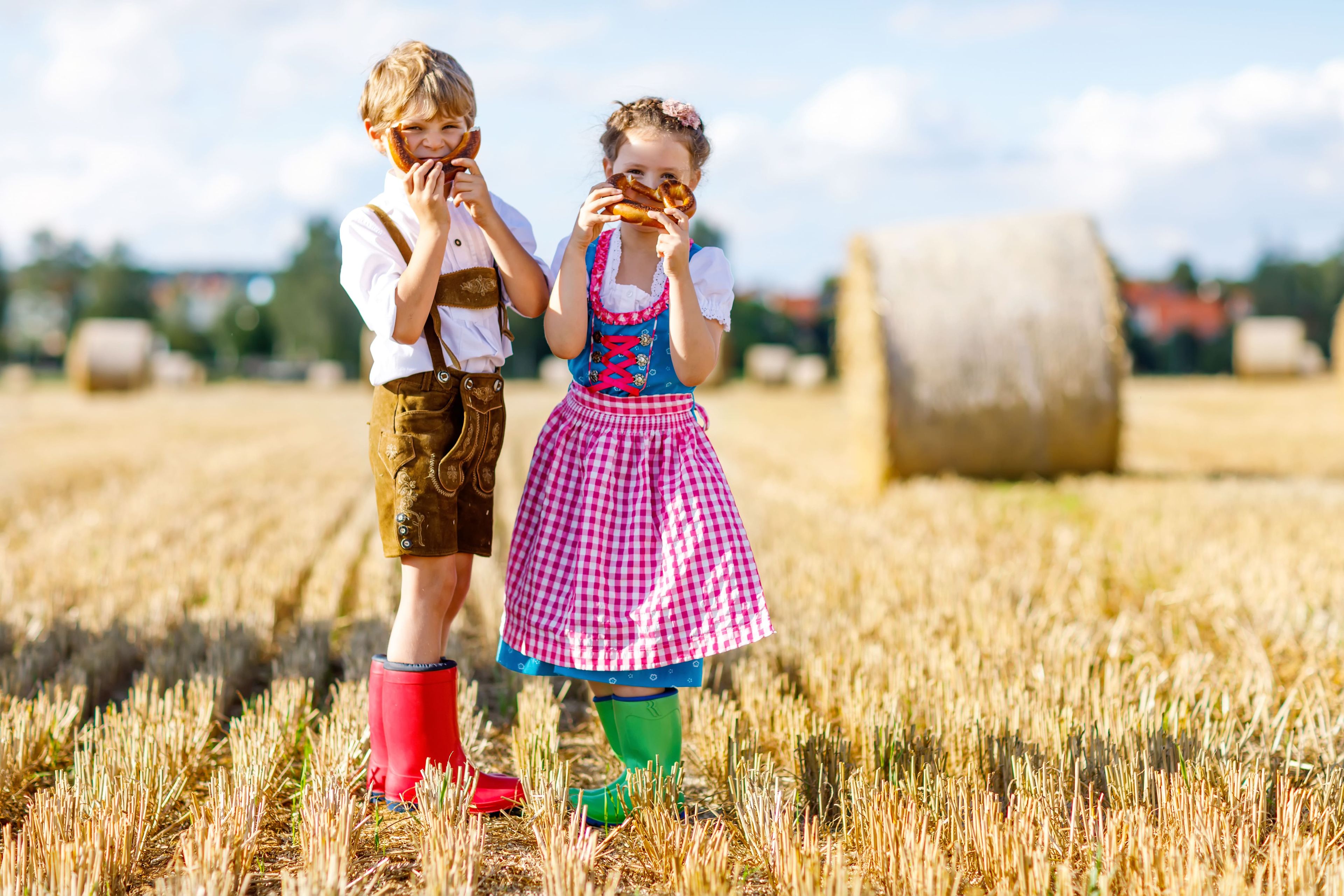 Bambini allegri con pretzel in costume tradizionale dirndl e lederhosen sul campo