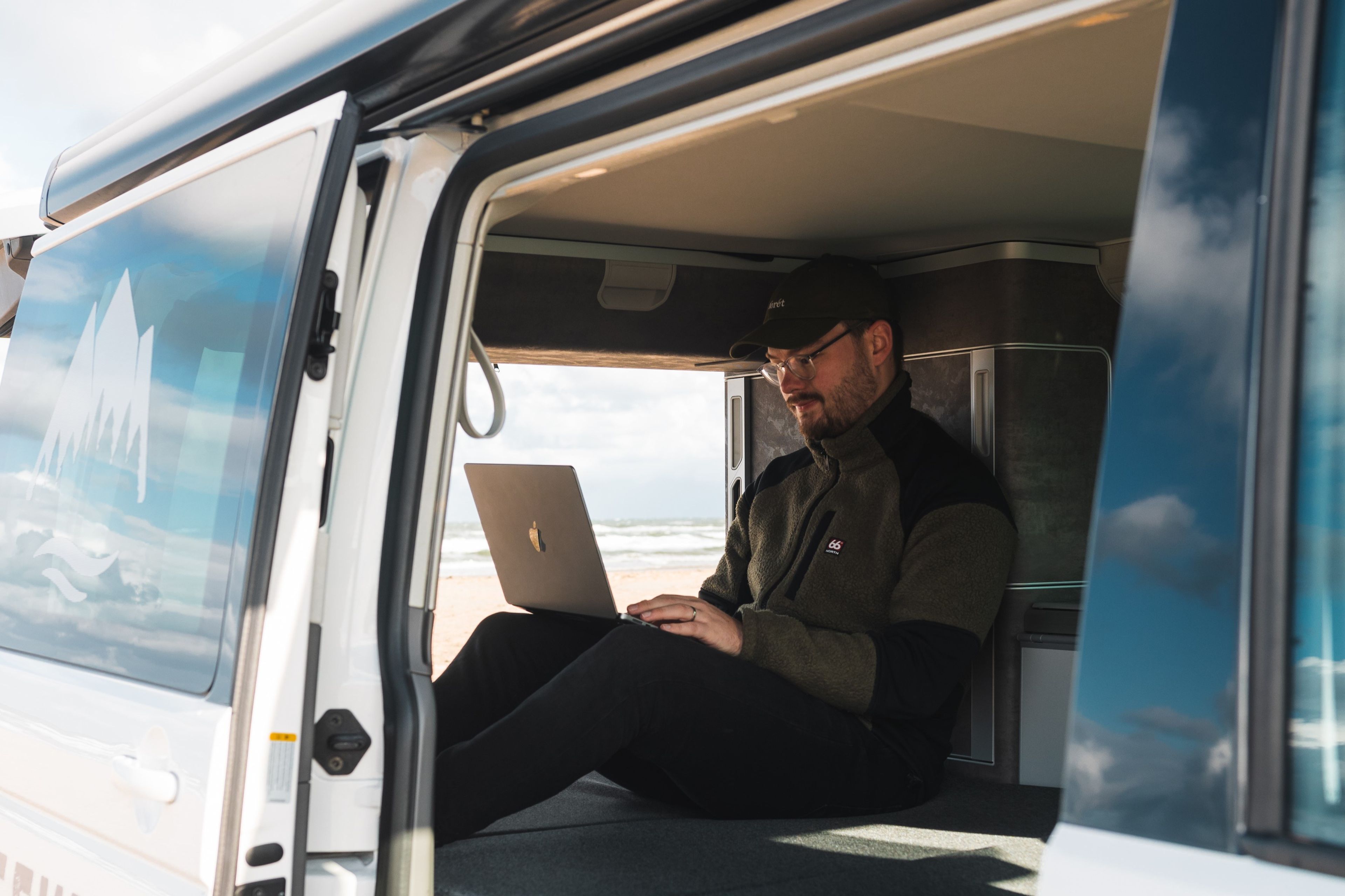 Ein Mann arbeitet in einem Campervan am Laptop.