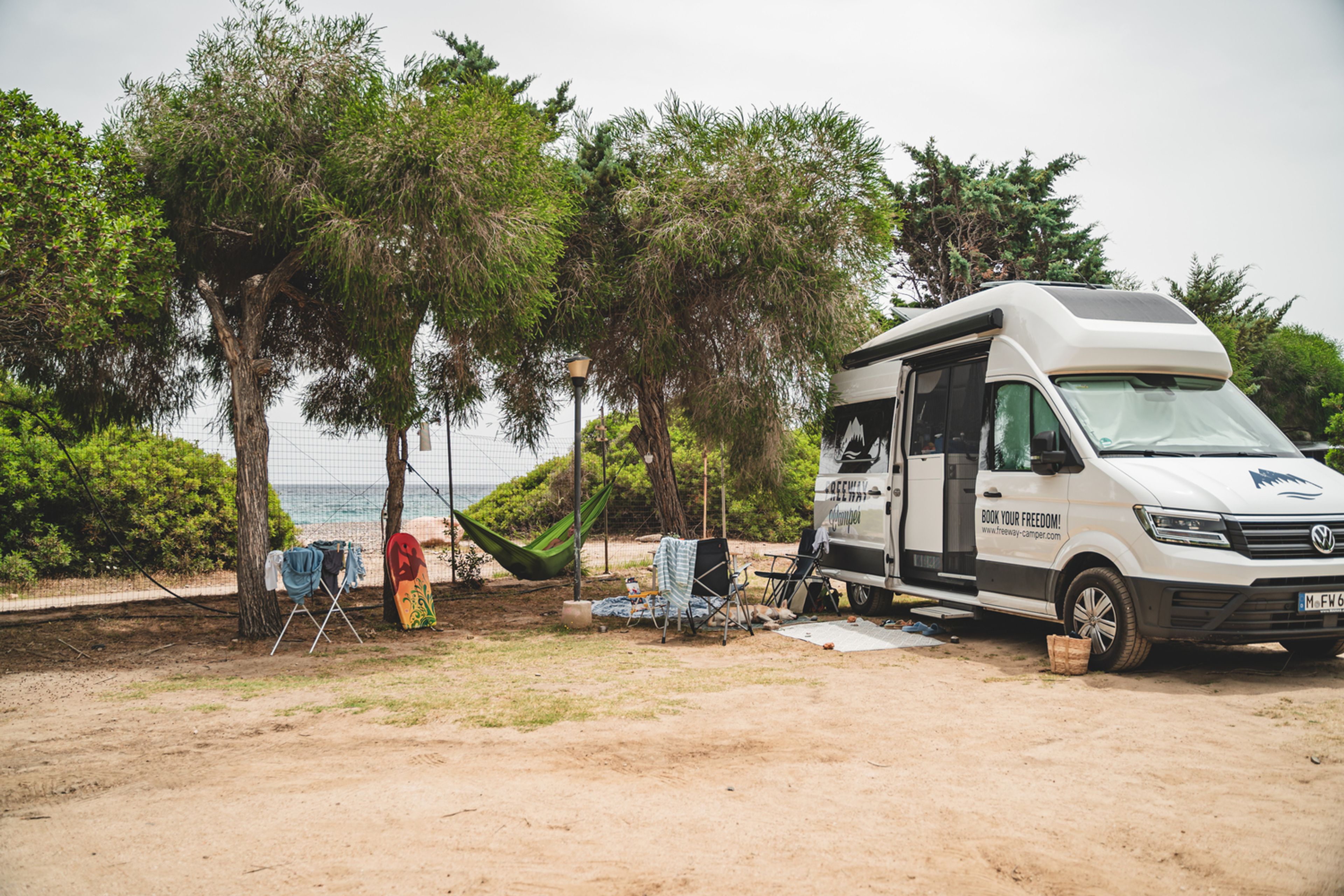 camper sul lungomare con amaca tra gli alberi e panni stesi al sole