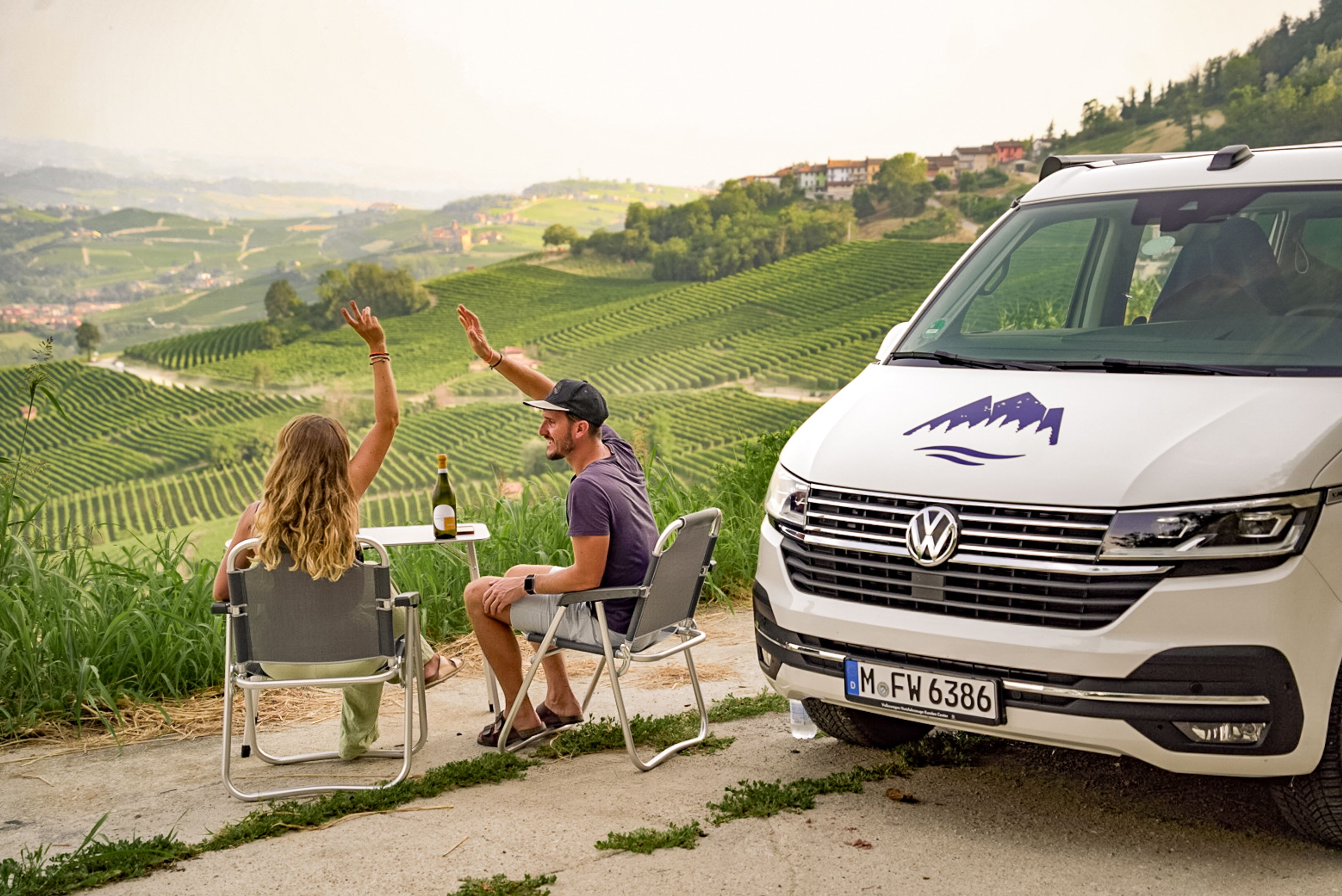 Pärchen mit VW Bulli hat Campingtisch und Stühle spontan ausgepackt