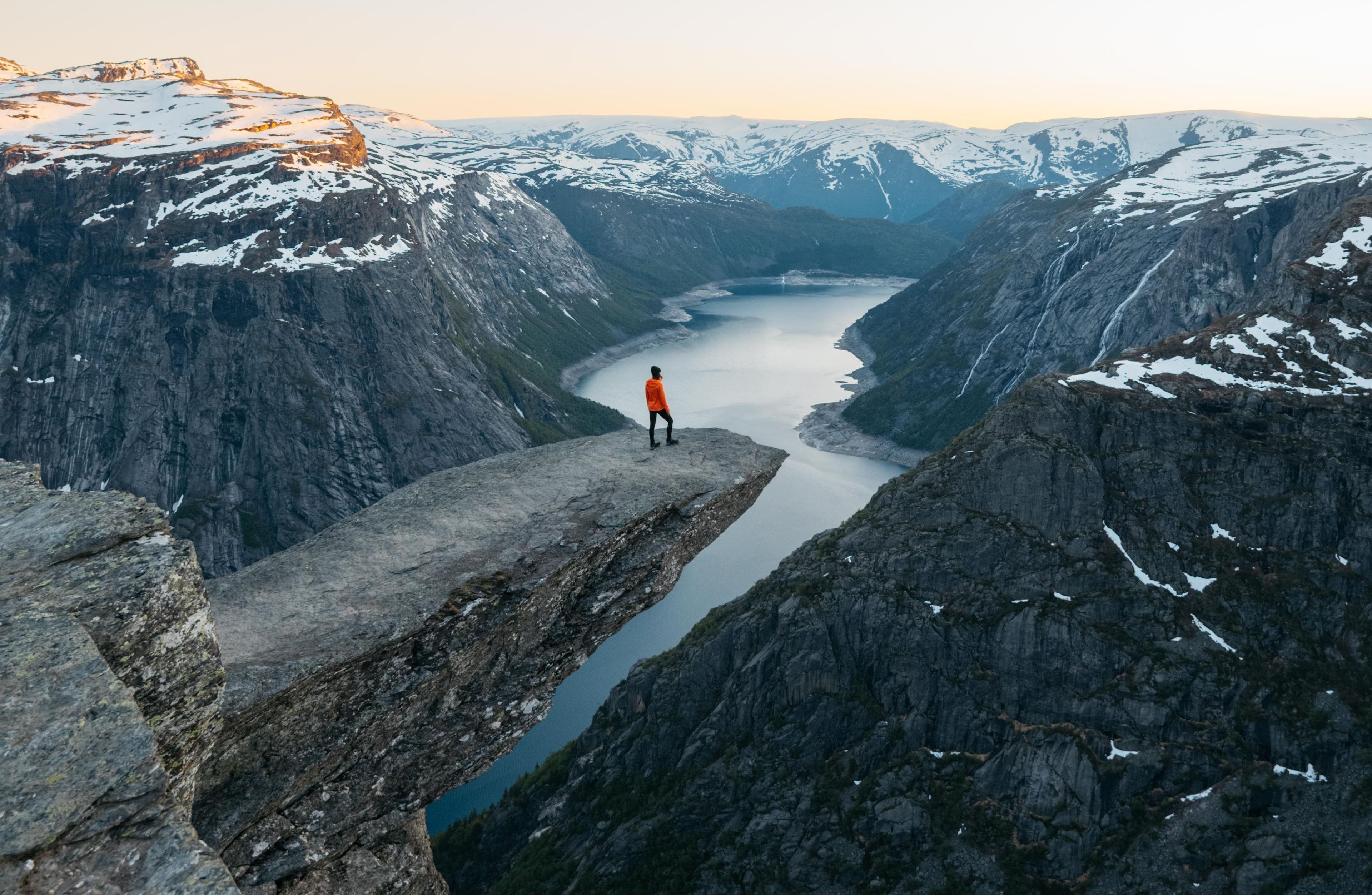 Frau steht an Klippe in Norwegen mit Bergen im Hintergrund