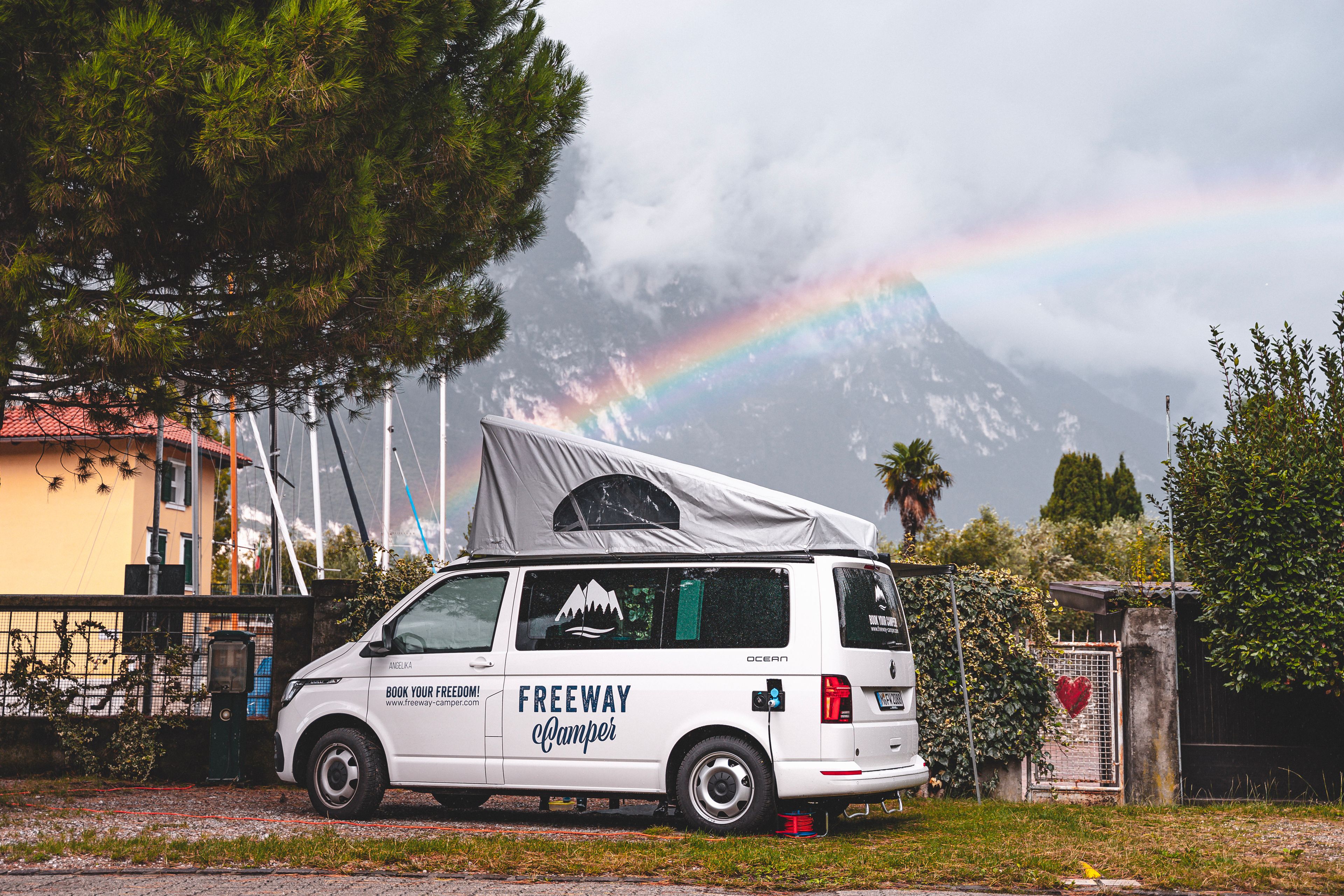 VW Bulli Ocean with pop-up roof and rainbow in background