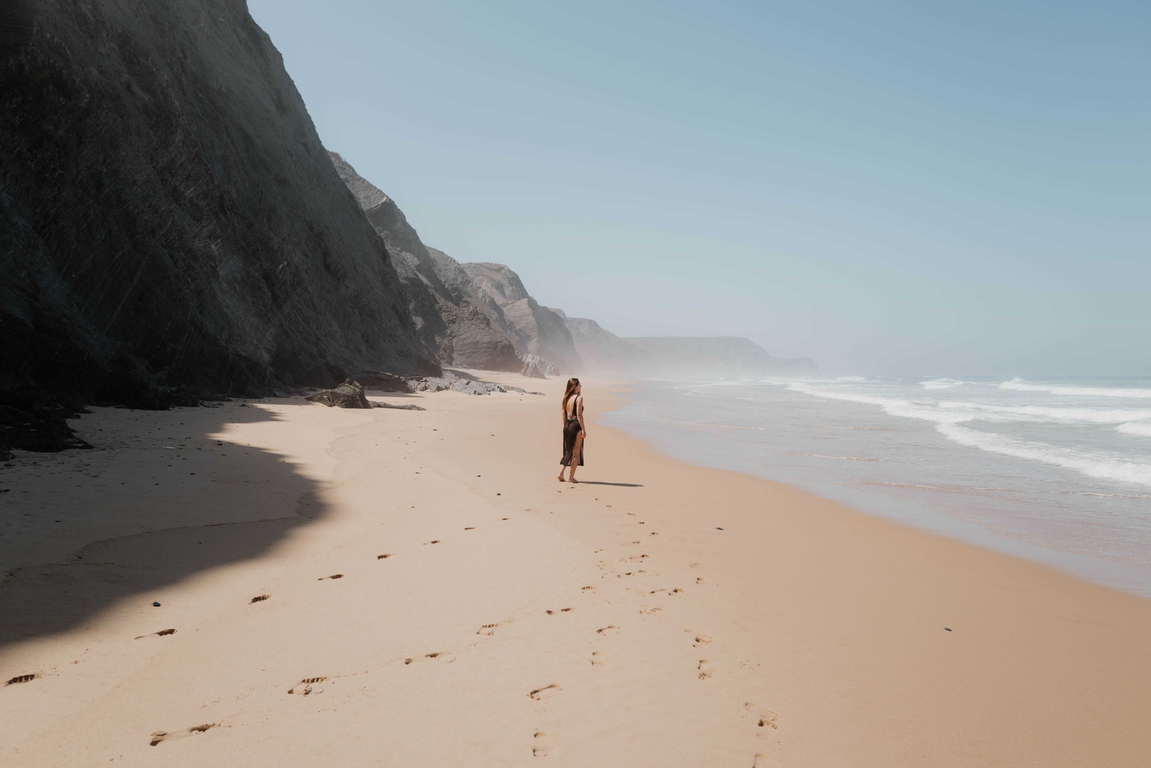 Elisabeth sulla spiaggia di sabbia Praia da Barriga con a lato la parete rocciosa